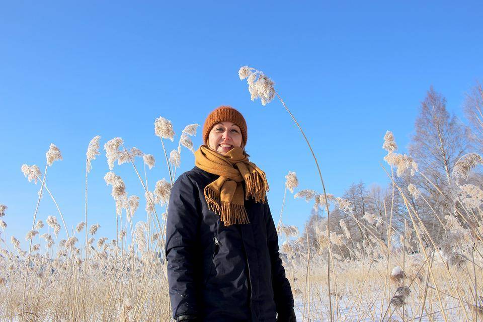 Saara Karkulahti seisoo talvisessa maisemassa ja katsoo hymyillen kameraan.