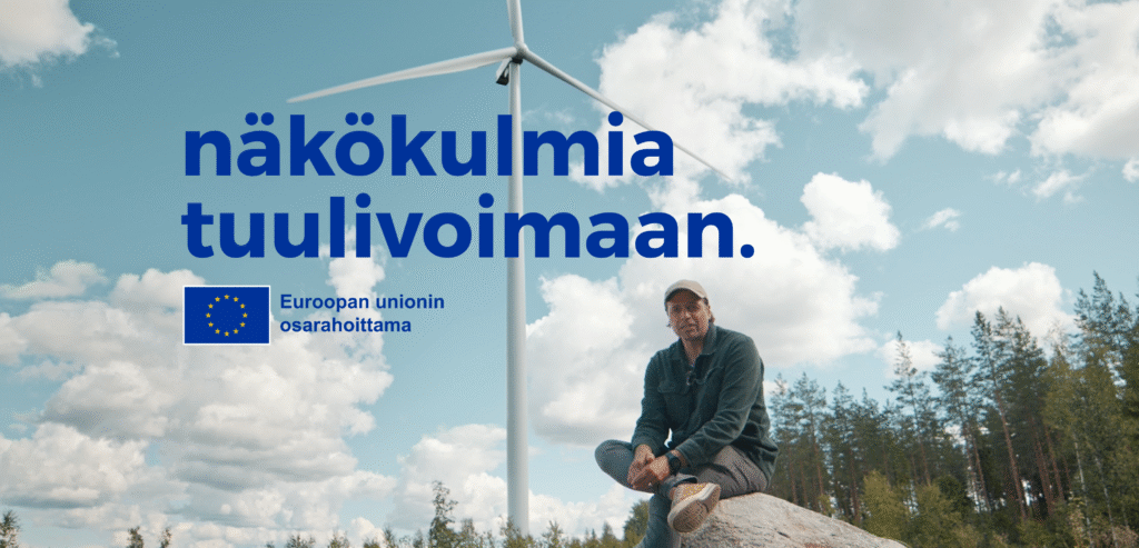 Kimmo Ohtonen istuu kivellä suomalaisessa maisemassa, jossa on tuulimylly taustalla.